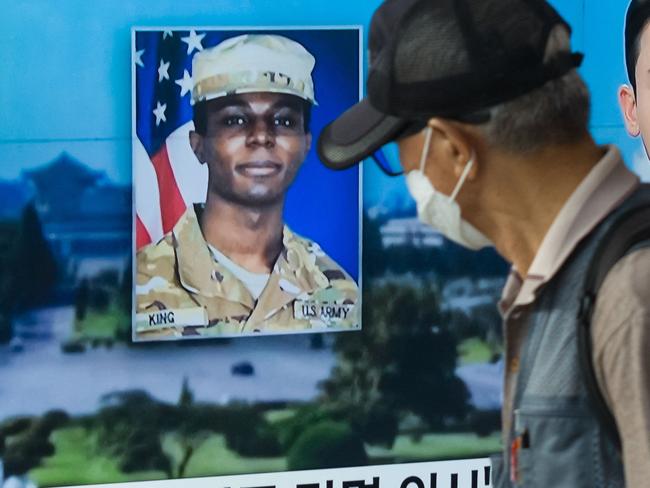 (FILES) In this photo taken in Seoul on August 16, 2023, a man walks past a television showing a news broadcast featuring a photo of US soldier Travis King (C), who ran across the border into North Korea while part of a tour group visiting the Demilitarized Zone on South Korea's border on July 18. North Korea has decided to expel US soldier Travis King, who was detained after crossing the border from the South in July, the KCNA state news agency said on September 27. (Photo by Anthony WALLACE / AFP)