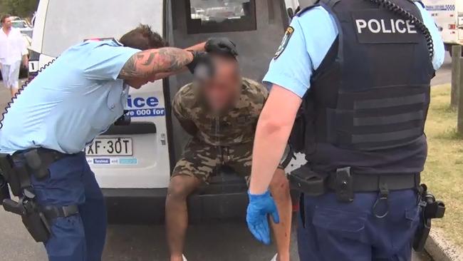 An officer pours water over the arrested man’s eyes after he was subdued by capsicum spray.