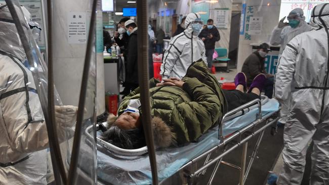 Medical staff wearing protective clothing arrive with a patient at the Wuhan Red Cross Hospital. Picture: AFP