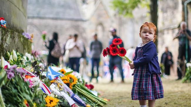 A young girl is seen laying flowers in remembrance of the late Queen Elizabeth. PIcture: Getty Images