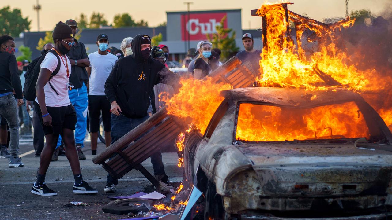 Protesters throw objects onto a burning car outside a Target store near the Third Police Precinct in Minneapolis, Minnesota. Picture: Kerem Yucel/AFP