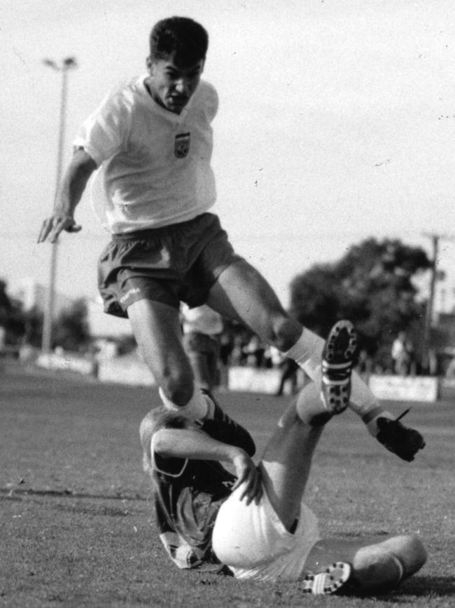 Stan Dacic, of Beograd Woodville, hurdles Ivica Jurkovic, of Adelaide Croatia, at Hanson Reserve in 1991.