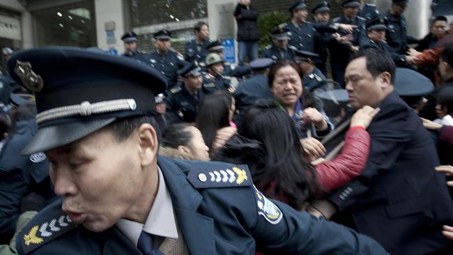 In this March 19, 2015 photo, security guards scuffle with protestors angry about failed investments with Hunan Bofeng Asset Management Ltd. outside of a branch of the Industrial and Commercial Bank of China in Changsha in southern China's Hunan province. Thousands of Chinese savers who entrusted money to an informal finance industry that operates with little government oversight are suffering painful losses as borrowers default and real estate and other ventures fail. (Chinatopix Via AP) CHINA OUT