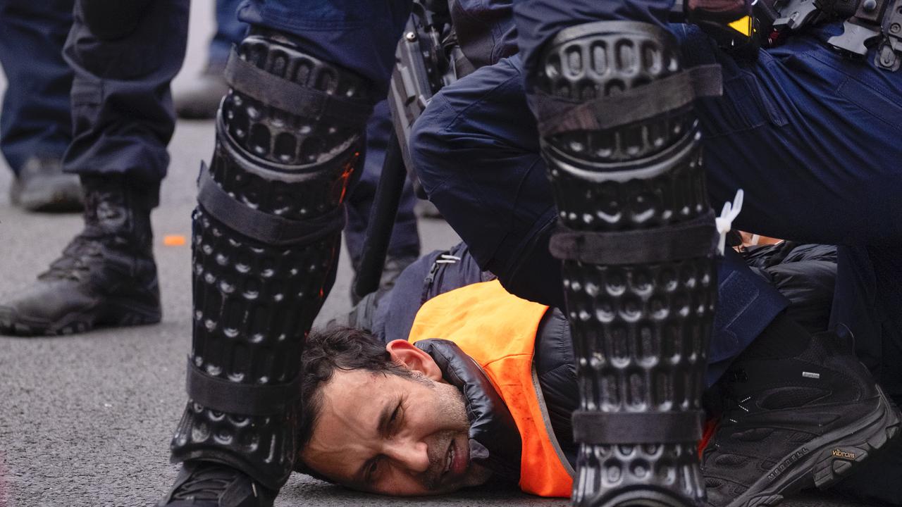 A protester is stopped by police outside the Land Forces event in Melbourne. Picture: NewsWire / Luis Enrique Ascui