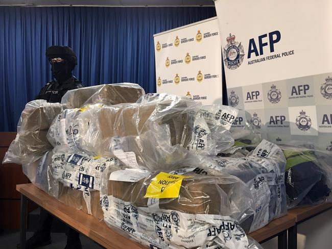 An Australian Federal Police Officer stands next to a pile of cocaine seized by police.