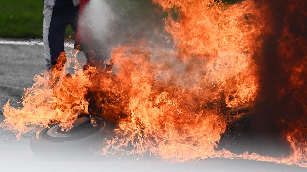 A track marshal tries to extinguish a motorbike on fire following.