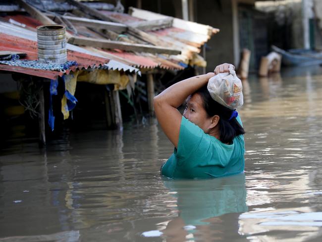 A resident wades through floodwaters after buying basic food items for dinner following flooding brought about by Typhoon Mangkhut which barrelled into northeastern Philippines. Picture: AFP