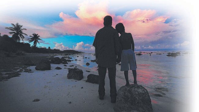 A refugee and his son watch the sunset on the beach in Nauru. Picture:  Lyndon Mechielsen/The Australian