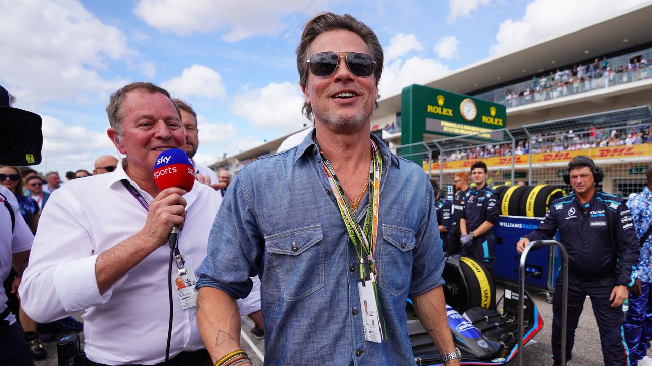 Brad Pitt walks past Martin Brundle. Photo by Alex Bierens de Haan/Getty Images for Williams Racing.