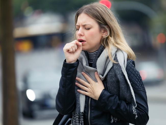 Shot of illness young woman coughing in the street.