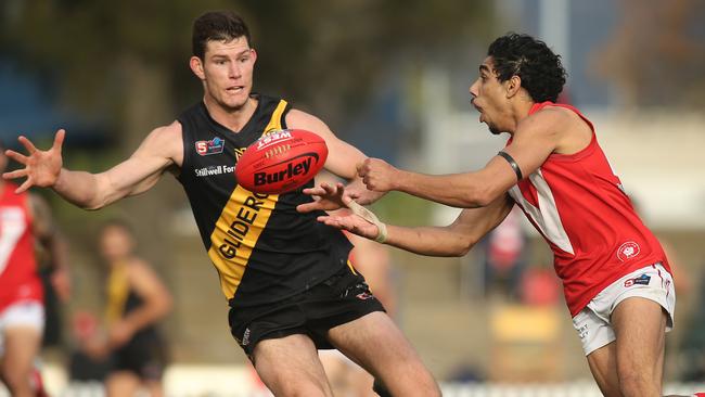 North’s Keanu Miller gets his handball away Glenelg’s Matthew Allen. Picture Dean Martin