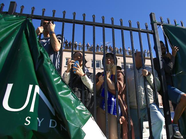 Spectators watch the match through a fence and atop an apartment block. Picture: AAP Image/David Gray