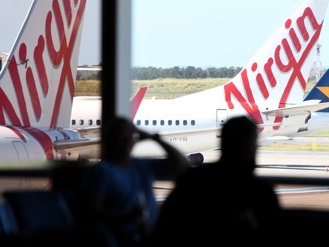 Two passengers wait for their charter flight at an empty Virgin Australia terminal at Brisbane domestic airport, Tuesday, April 21, 2020. The airline has announced this morning it has gone into voluntary administration but will continue to operate. (AAP Image/Dan Peled) NO ARCHIVING