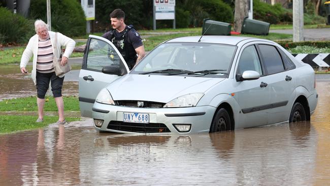 Traralgon floodwater cuts off roads and homes. An elderly woman is rescued by a police officer after driving into flood water and stalling her car. Picture: David Caird