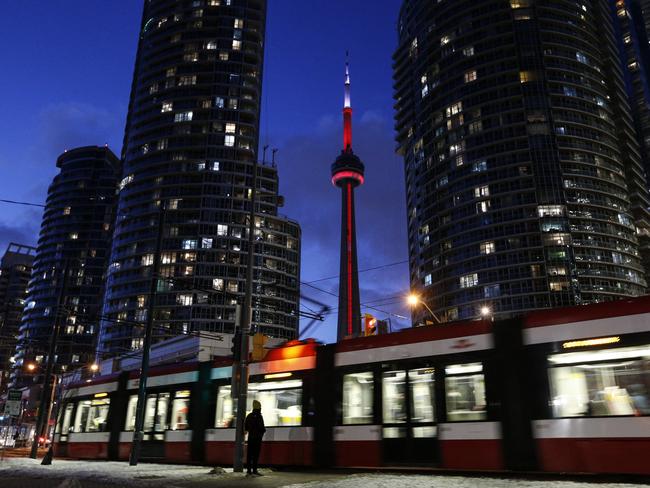 TORONTO, ON -  FEBRUARY 8: A pedestrian waits to cross Queens Way West while the Toronto turns to night behind them and the CN Tower.        (Photo by Paige Taylor White/Toronto Star via Getty Images)