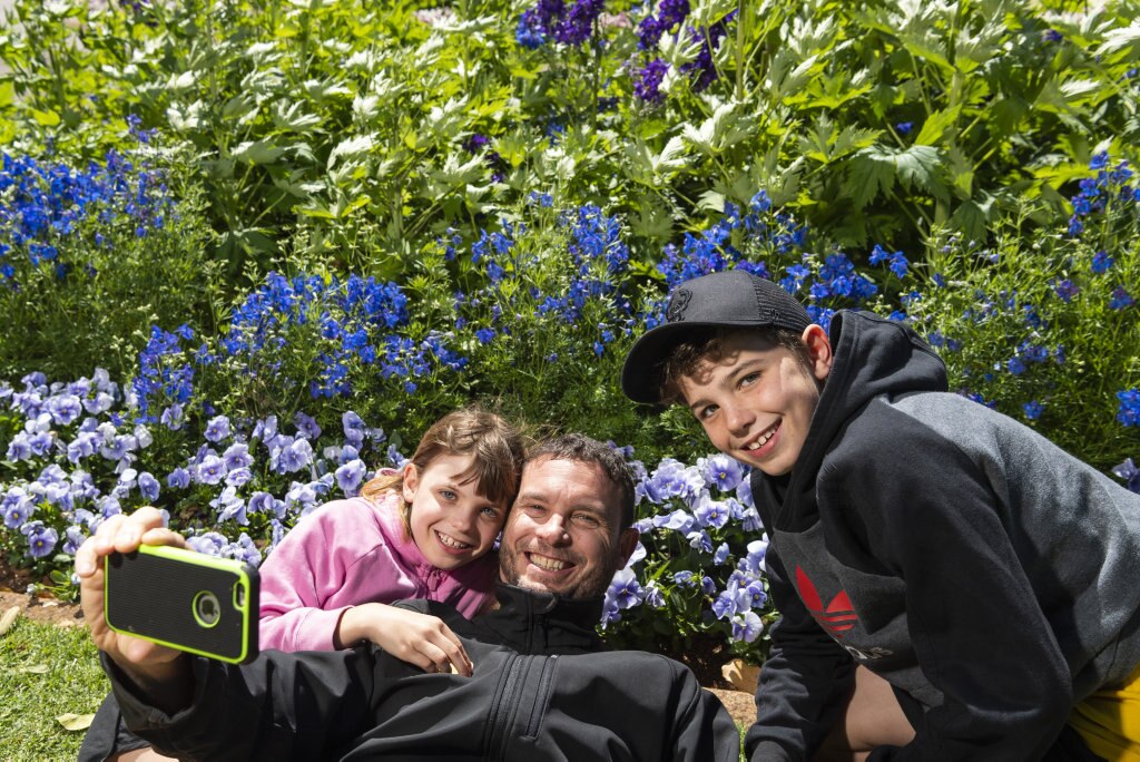 Recording their visit to Queens Park are (from left) Lorelei Pawsey, Warwick Pawsey and Lachlan Pawsey during Carnival of Flowers 2020, Saturday, September 26, 2020. Picture: Kevin Farmer