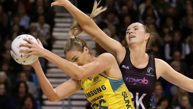 Australia's Caitlin Bassett, left, takes the ball as New Zealand's Kelly Jury attempts to block.