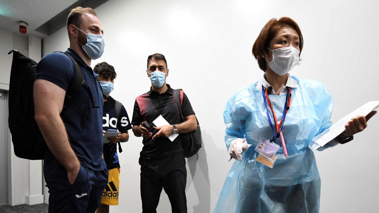 Three members of the Olympic refugee team, Ahmad Alikaj (L), Abdullah Sediqi (2nd L) and coach Alireza Nassrazadany (3rd L) are checked by a quarantine officer upon their arrival at Narita international airport in Narita, Chiba prefecture on July 14, 2021. (Photo by Kazuhiro NOGI / AFP)