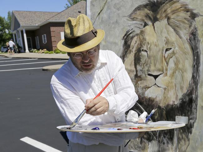 Outpouring of grief ... Mark Balma works on a mural of Cecil the lion outside Dr Walter James Palmer's dental office in Bloomington, Minnesota. Authorities allege that Palmer paid $50,000 to track and kill Cecil, a protected lion, just outside Hwange National Park in Zimbabwe. Picture: AP