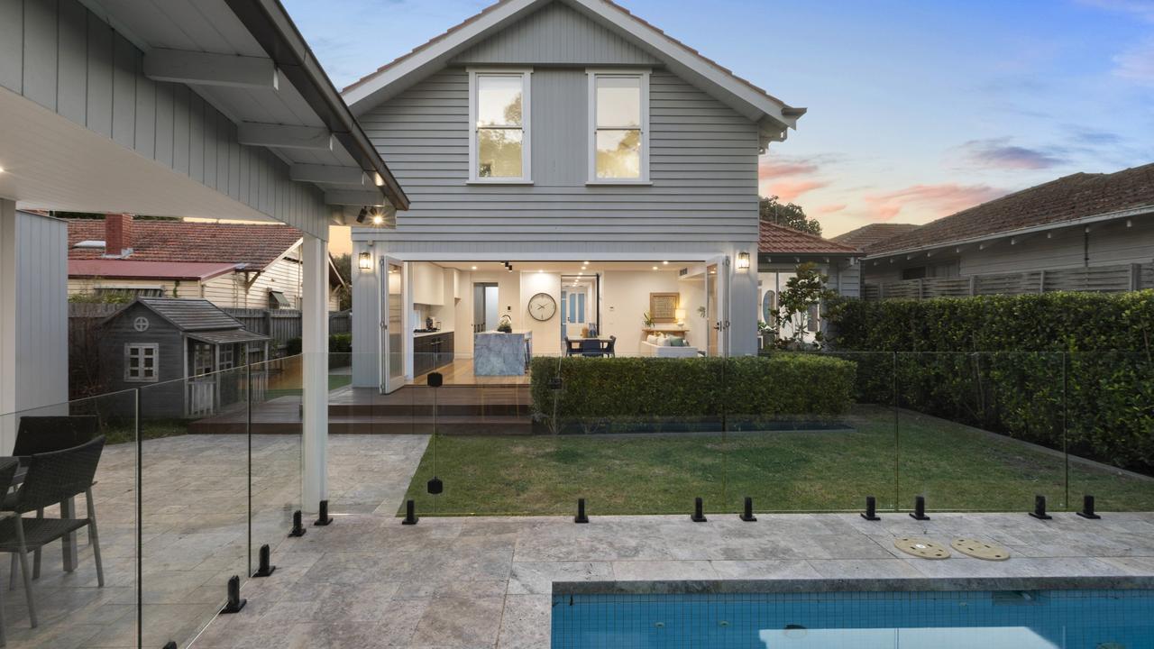 Full-width bi-fold doors connect the living space to a stunning al fresco deck, solar-heated pool, and manicured lawn.