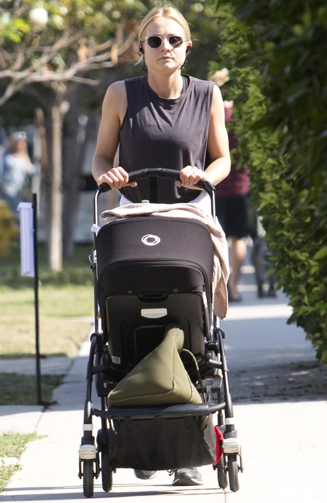 Tessa James with earphones in as she goes for a walk, with the baby in the pram. Picture: DIIMEX