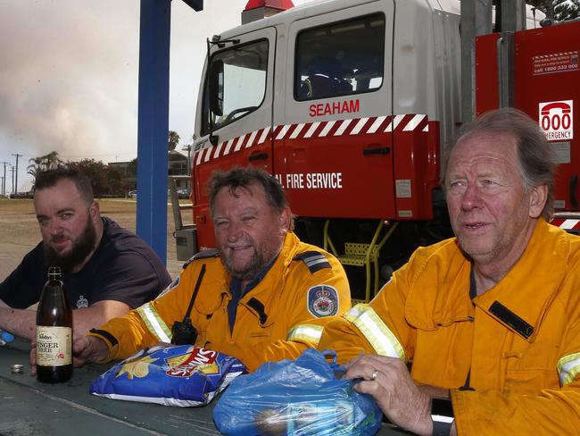 Seaham RFS crew members Scott Jenkinson, Chris Young and Rod Irwin take a break after fighting a blaze at Wallaby Point, on Saturday. Picture: Darren Pateman