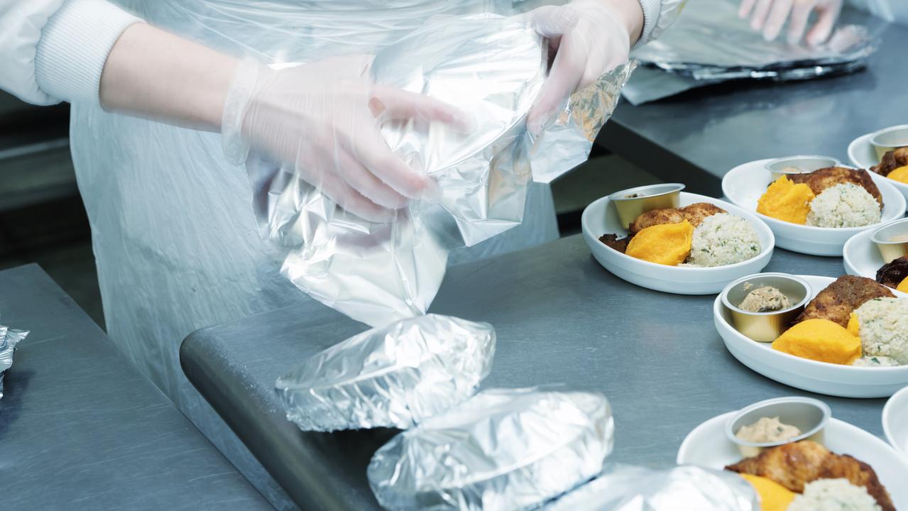 Chef is wrapping airline food in foil before being loaded on to a plane.