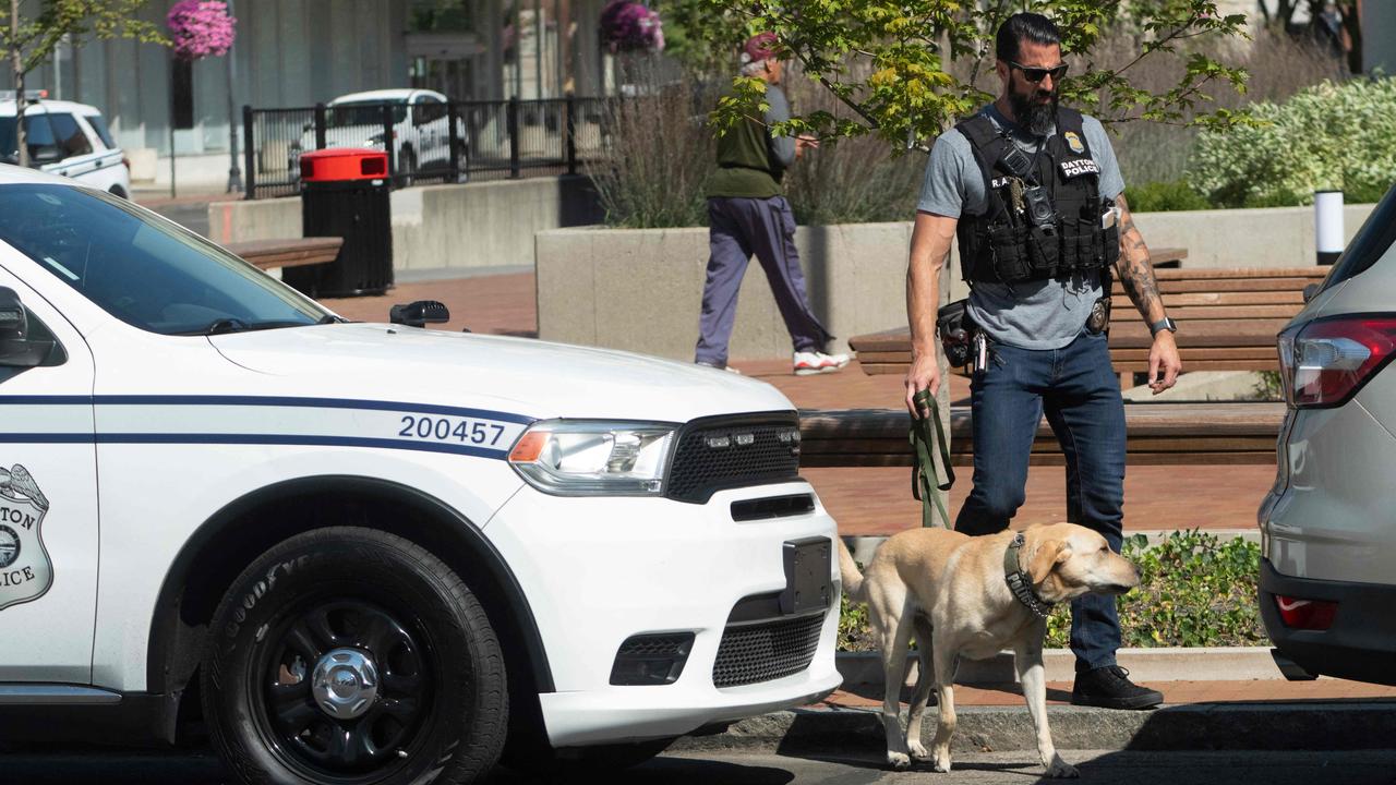 A Dayton police officer and his dog return to their vehicle after sweeping the Springfield City Hall grounds for explosives. Picture: Roberto Schmidt/AFP