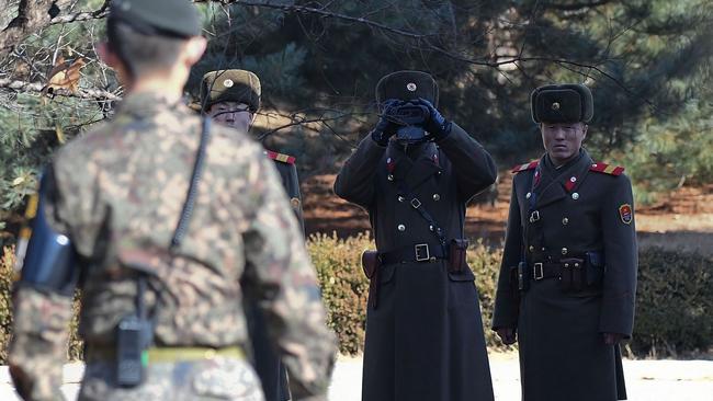 North Korean soldiers, watched by a South Korean soldier, look across to South Korea in ‘Truce Village’. Picture: Korea Pool/Getty Images