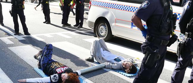 Sergio and Ebony protesting government inaction on climate change by attaching themselves to the road in Post Office Square, Brisbane, sparking a police response. Picture: Liam Kidston.