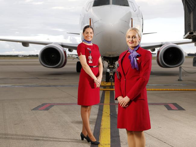 Virgin staff Alahna Wilkinson and Alice Whittle posing in front of Long Beach, 737-800 at the Brisbane Domestic Airport.