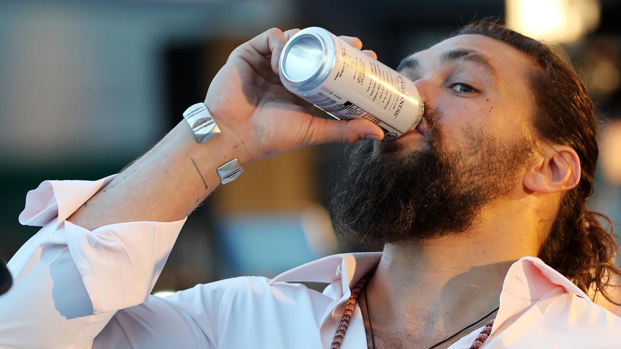 Jason Momoa downs a beer at the Australian premiere of Aquaman. Picture: Nigel Hallett