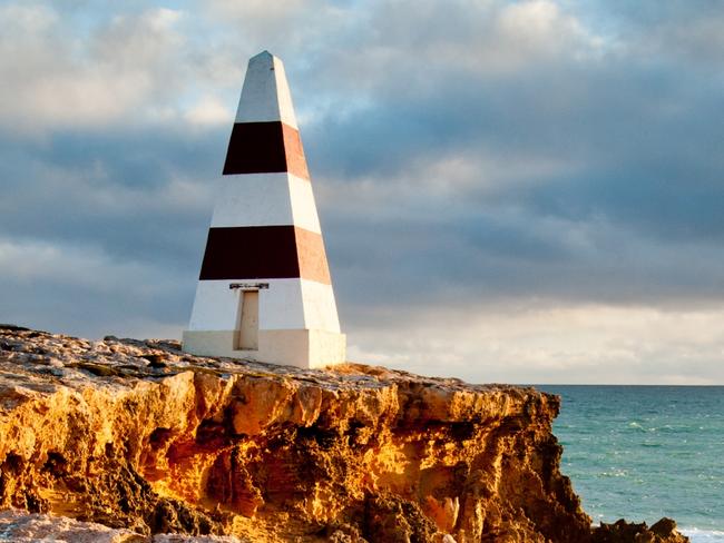 Robe Obelisk with stormy clouds and sun setting on cliffs and rocky coastline, Limestone Coast, South East, South Australia. Picture: Getty Images