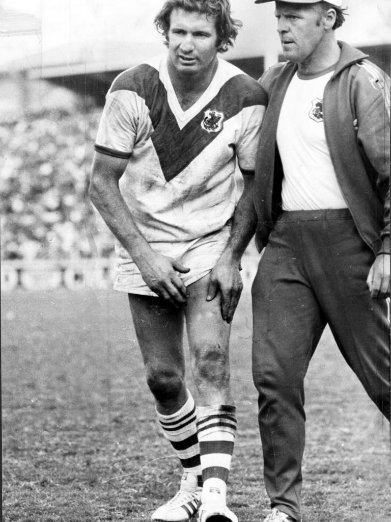 In his controversial white boots, Graeme Langlands comes from the field with a leg injury in the 1975 grand final.