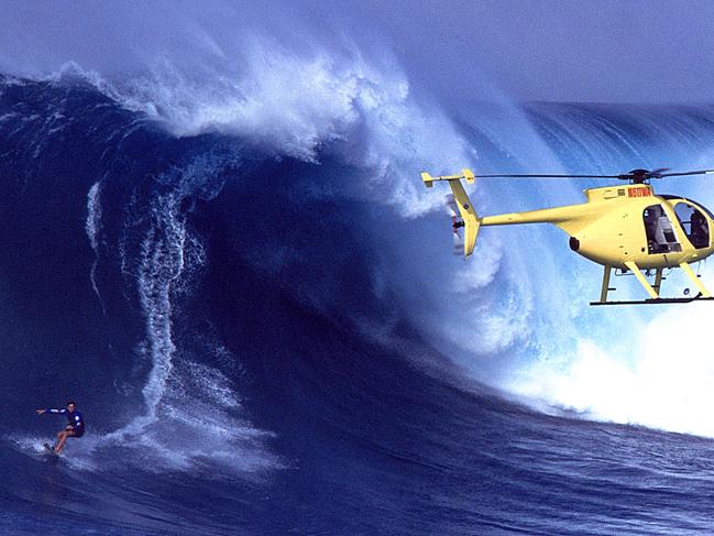 Clarke-Jones of Australia drops into a 30-foot plus wave as a helicopter hovers during the Jaws Tow-In Competition in Pe'Ahi, Maui, Hawaii. Photo: Donald Miralle/Getty Images