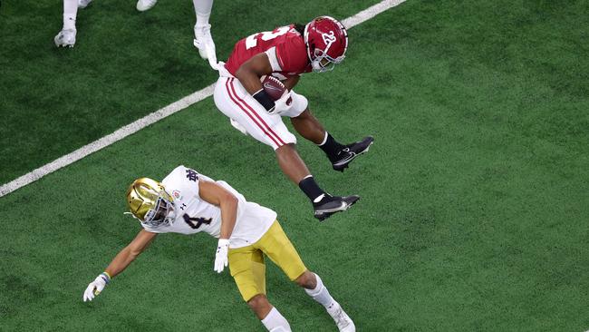 ARLINGTON, TEXAS - JANUARY 01: Running back Najee Harris #22 of the Alabama Crimson Tide leaps cornerback Nick McCloud #4 of the Notre Dame Fighting Irish during the first quarter of the 2021 College Football Playoff Semifinal Game at the Rose Bowl Game presented by Capital One at AT&amp;T Stadium on January 01, 2021 in Arlington, Texas. (Photo by Carmen Mandato/Getty Images)