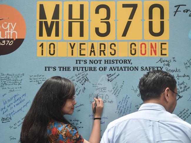 A woman writes a message during an event held by relatives of the passengers and supporters to mark the 10th year since the Malaysia Airlines flight MH370 carrying 239 people disappeared from radar screens on March 8, 2014 while en route from Kuala Lumpur to Beijing, in Subang Jaya on March 3, 2024. (Photo by Arif Kartono / AFP)