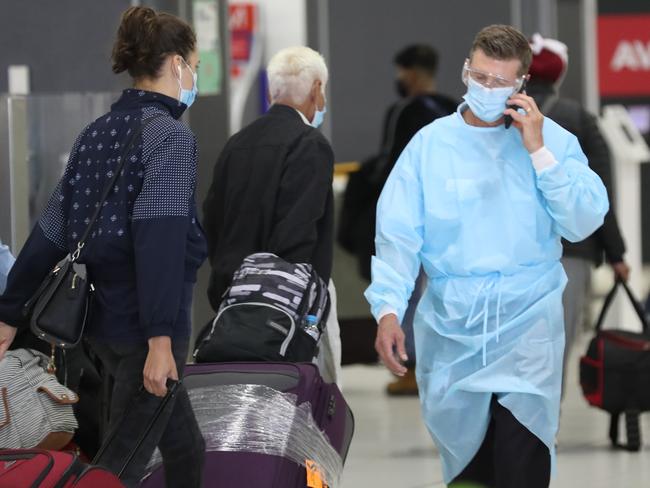 People arrive at Melbourne Airport from their Brisbane flights  where a COVID lockdown has begun.A man in PPE is seen in the baggage area. Friday January 8, 2021. Picture: David Crosling