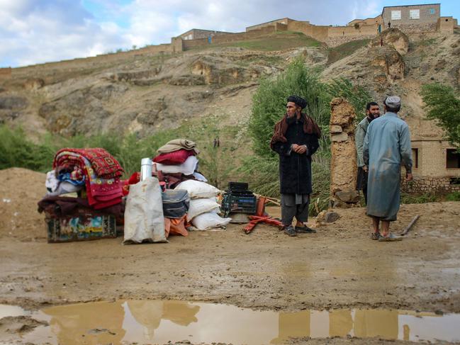 Afghan men stand beside their belongings kept near a damaged house after flash floods following heavy rainfall in Firozkoh, Ghor province. Picture: AFP