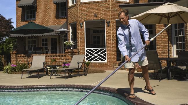 Man cleaning a pool.Real estate, house with a pool