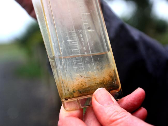 John Brumby holds his rain gauge on his farm.