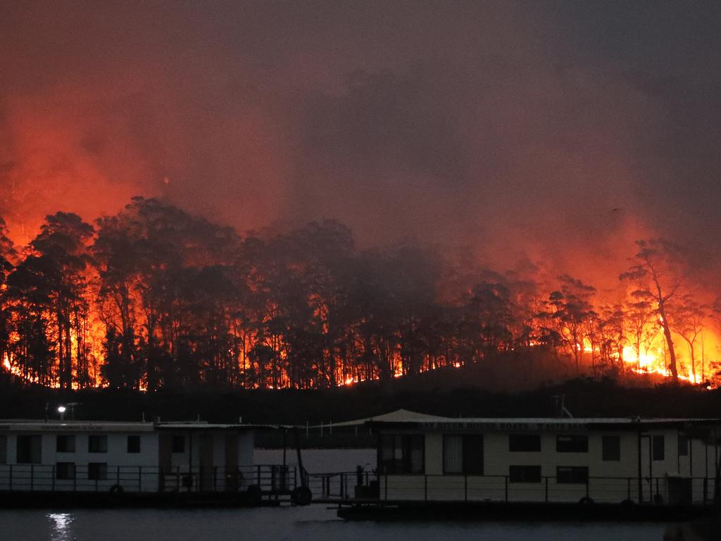 A slow burning fire moves down to the north western edge of the Clyde River in Batemans Bay. Picture: John Grainger