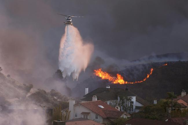 The upscale neighborhood of Pacific Palisades remains blanketed by a thick cloud of black smoke that blots out the sun