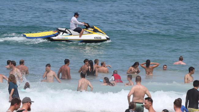 Lifeguard James Watson negotiates crowds at Surfers Paradise Beach. Picture: Mike Batterham