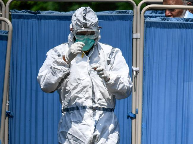 A health official wearing protective gear holds a swab after taking a sample from a man at the drive-through screening and testing facility in Islamabad, Pakistan. Picture: AFP