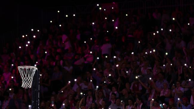 Fans hold torches as a power cut affects Netball SA stadium. (Photo by Graham Denholm/Getty Images)