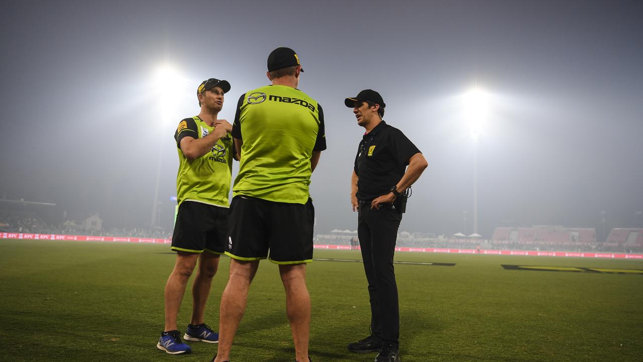 Officials are seen on the field of play as smoke haze forced the stoppage of the match between the Sydney Thunder and the Adelaide Strikers at Manuka Oval. Photo: Lukas Coch