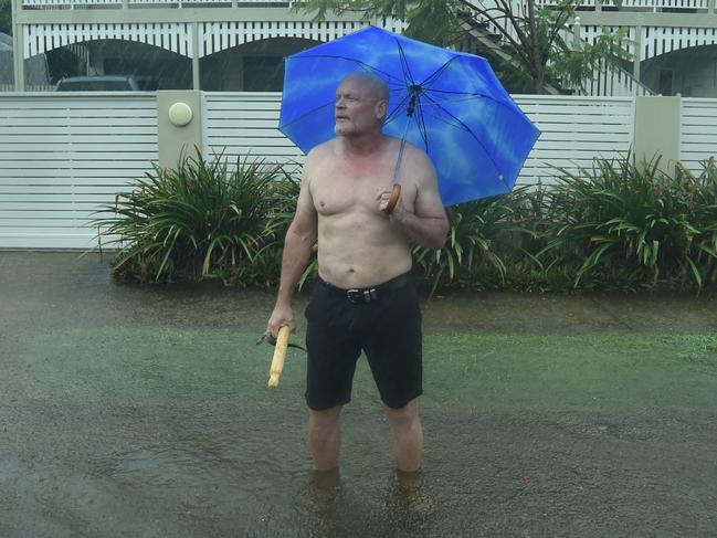 Heavy rain lashes Townsville causing flash flooding. Pimlico resident John McGuire tries to get cars to slow down in the flooded road outside his home in Palmerston Street. Picture: Evan Morgan