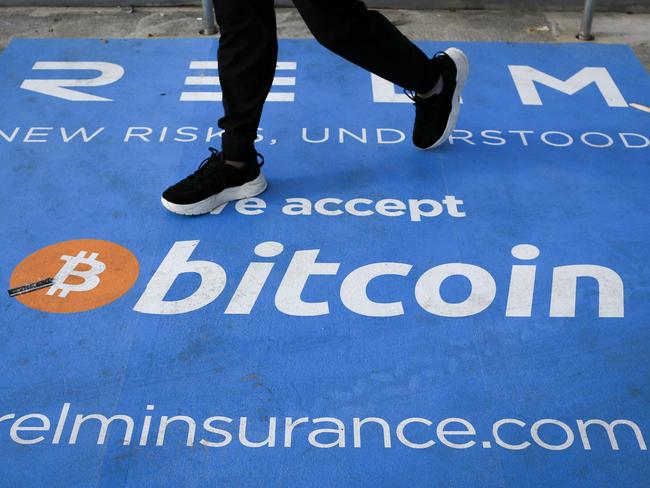 (FILES) In this file photo taken on June 04, 2021, a man walks past a banner with the logo of bitcoin during the crypto-currency conference Bitcoin 2021 Convention at the Mana Convention Center in Miami, Florida. - The US Justice Department announced on February 8, 2022, it had recovered more than 94,000 bitcoin stolen in 2016, currently valued at $3.6 billion, a record seizure. (Photo by MARCO BELLO / AFP)