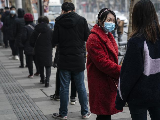 Residents wear masks while queuing to buy milky tea in Wuhan during one of the city’s lockdowns. Picture: Getty Images